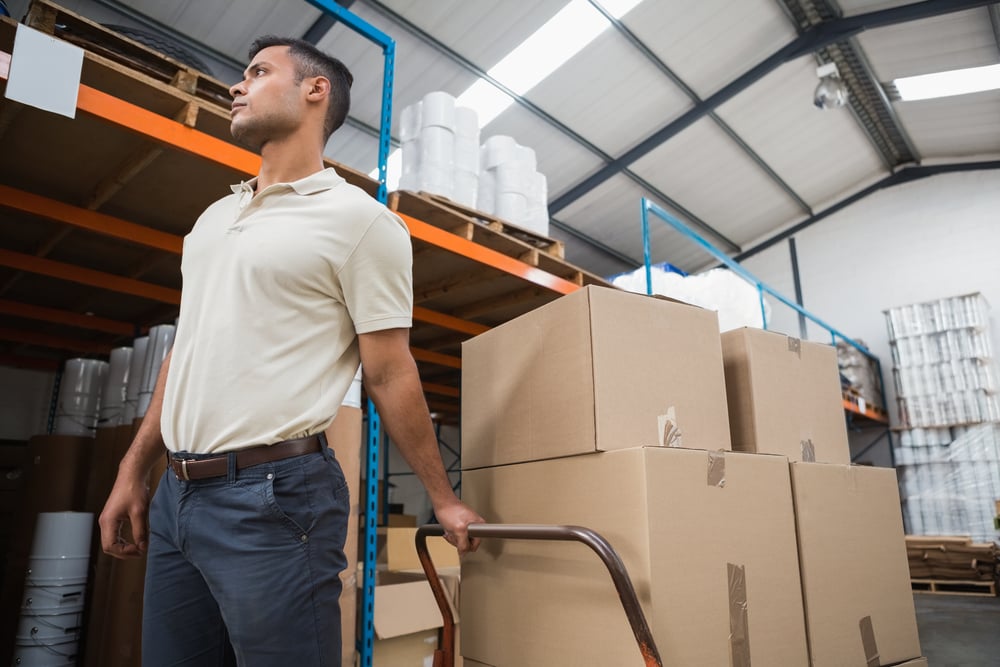 Worker pushing trolley with boxes in warehouse Worker pushing trolley with boxes in warehouse